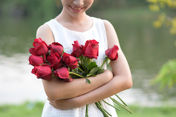 Woman hugging red roses with pleasure.