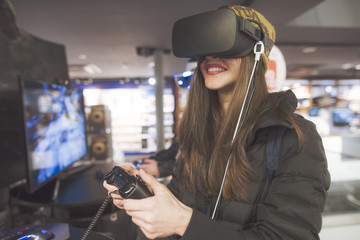 beautiful young woman trying a virtual reality device in a retail electronics store