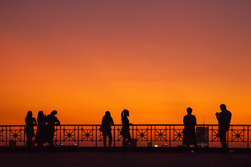 Naklejka na ściany i meble Silhouette people on background red sunset on observation desk.
