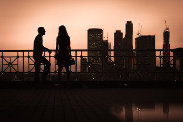 Silhouette couple of young guy and girl on background big city at sunset. Toning color.
