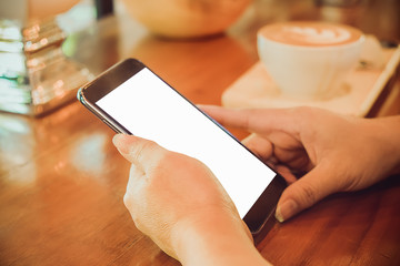 woman hand holding using smartphone in coffee shop, vintage tone