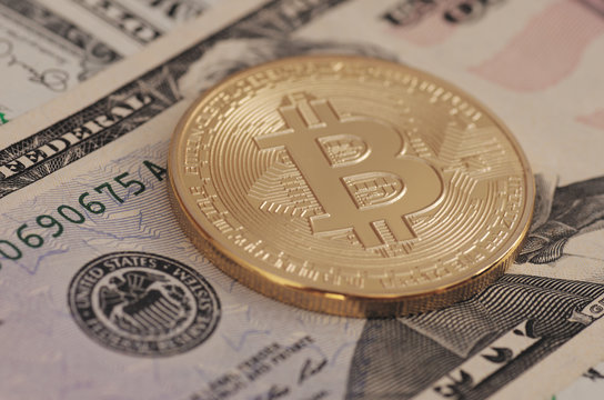Golden plated Bitcoin on US dollar bills.