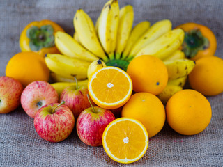 fruits apples oranges banana plums on brown hemp sack texture background