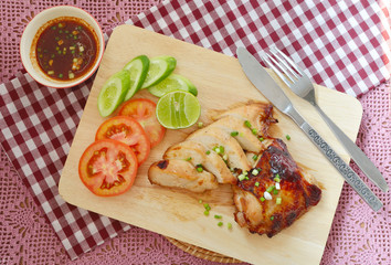 Roast Chicken with tomatoes, cucumbers, lemon and spicy sauce dip on a cutting board