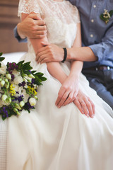 The groom embracing bride in white wedding dress