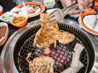 Streaky pork grilling on charcoal stove.