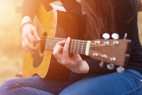 Woman's hands playing acoustic guitar, close up and select focus