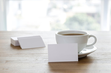 Blank business cards and cup of coffee on wooden table.
