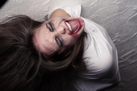 screaming crazy woman with flying hair in straitjacket
