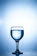 Glass glass of water on the isolated background. Mountain mineral pure mountain water with gas bubbles and a spray tonic refreshing sports drink.