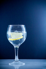 Glass glass of water with lemon on the isolated background. Mountain mineral pure mountain water with gas bubbles and a lemon slice and spray tonic refreshing sports drink.