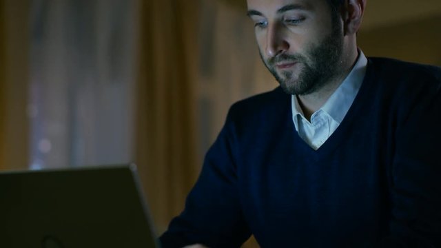Close-up of a Middle Aged Man Working on a Laptop. He's at Home. In the Background His Flat Looks Stylish but Warm. Shot on RED EPIC-W 8K Helium Cinema Camera.