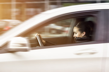 Side view of a woman driving a car. Woman driving fast. Beautiful woman speeding in a automobile.