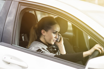 Talking on the phone while driving. Beautiful woman making a phone call in her car.