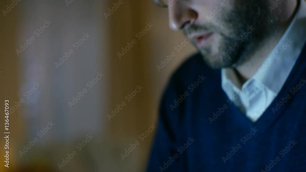 Poster close-up of a middle aged man working on a laptop. he's at home alone. computer's screen reflects in