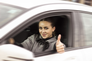 Beautiful blonde woman giving thumbs up. Woman driving off in her car and saying a good job. Gorgeous blue eyed blonde in a car.