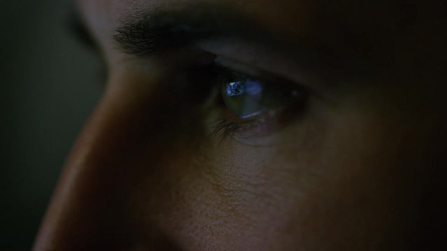 Close-up of a Green-Blue Man's Eyes with Screen Reflecting in Them. He's Illuminated with Different colours. Shot on RED EPIC-W 8K Helium Cinema Camera.