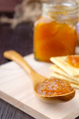 Orange jam on wooden background