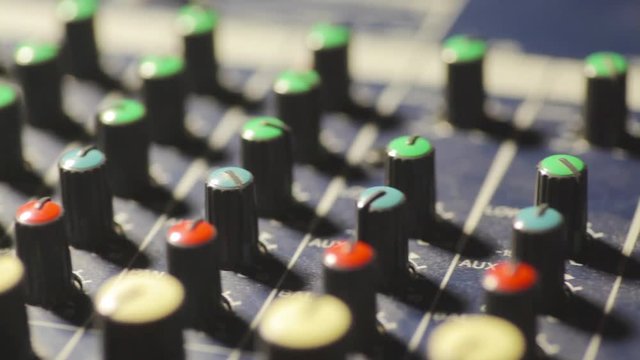 Dolly shot video of a mixer desk with many buttons.