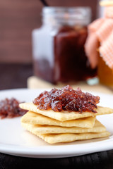 Crackers with grape jam on wooden background
