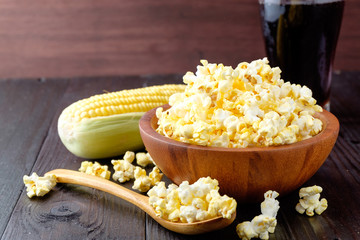 Popcorn in a bowl on wooden background.