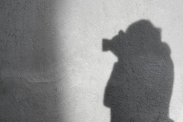 Shadow of unrecognizable,unknown photographer with camera on the white wall.
Textured,...