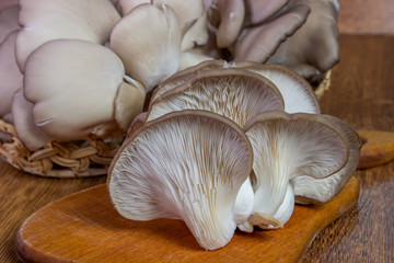 Fresh oyster mushroom on the board, horizontal front view. Healthy oyster mushroom. Basket with mushrooms.