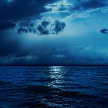 dark clouds in night with moonlights over water