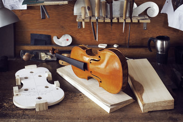 Incomplete violin and planks on workbench in workshop