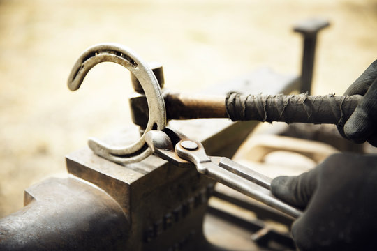 Cropped of farrier making horseshoe on anvil