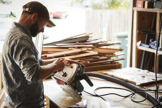 Craftsperson checking circular saw while working in workshop