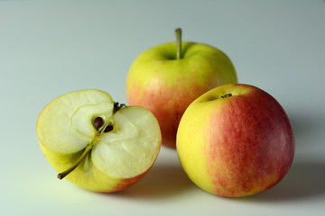 Three ripe apples on white background - one apple cut in half