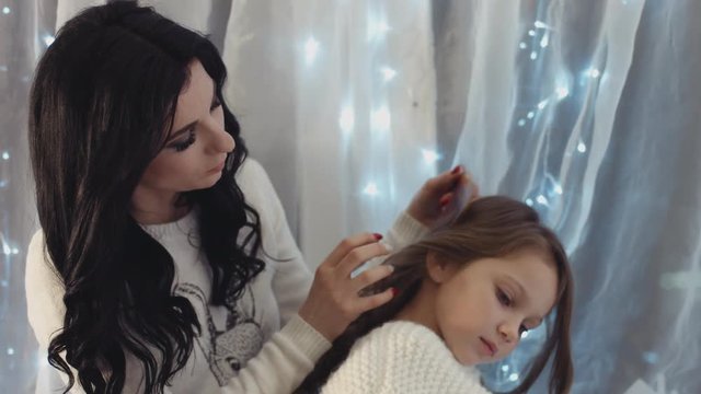 Mother combing hair of her little daughter