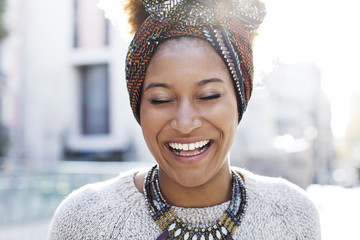 Cheerful woman wearing headscarf while standing on city street