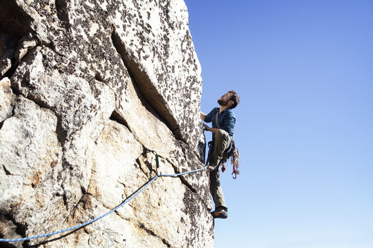 Low angle view of man rock climbing against clear sky