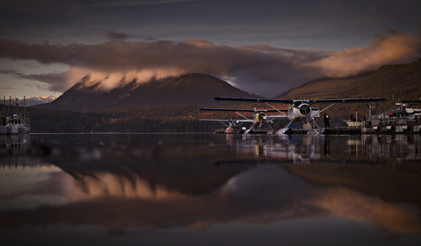 Biplanes parked in lake against mountain during sunset