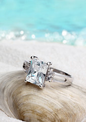 Jewelry ring with clean diamond on sand beach background, soft f