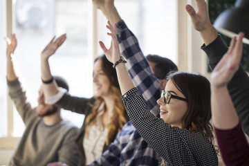 Students raising hands while sitting at table in classroom