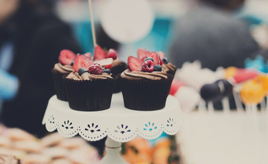 Beautiful cupcakes with berries closeup on banquet table.