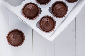 beautiful brown delicious chocolate muffins in a white box delivery food on wooden background close-up