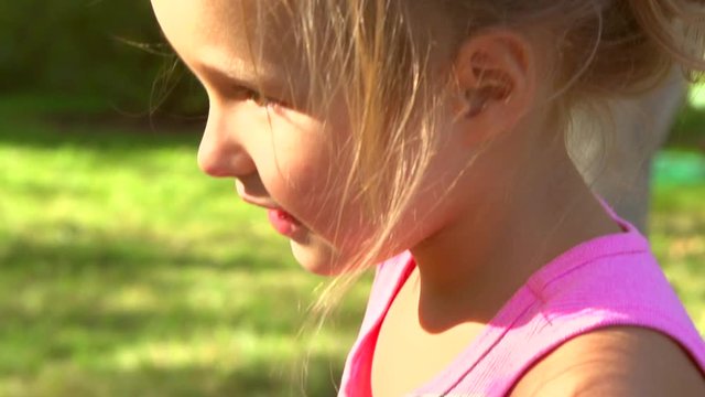 Portrait of a smiling little girl close up. Cute four years old child enjoying nature outdoors. Healthy carefree kid playing outside in summer park. Full HD 1080p. High speed camera, slow motion