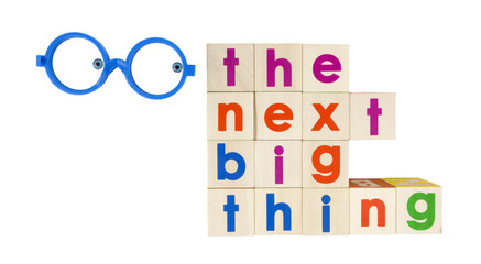 THE NEXT BIG THING concept spelled with colorful toy blocks with glasses and eyes ogling the text. Isolated.