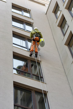 A Man Cleaning Mirror Window On A High Rise Building.Climber On Job As Professional Windows Cleaner