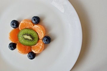 Fruit flower with green kiwi and orange tangerines on the white table