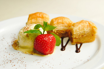 Melted ice cream under the slice of cinnamon with fresh strawberries and baklava with icecream strawberries and mint poured chocolate strawberry sweet baklava chocolate cream sprinkled with cinnamon