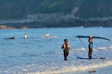 Naklejka premium Deux jeunes surfeurs s'avancent dans l'eau pour pratiquer le surf