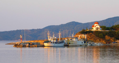 Picturesque summer landscape of boats and orthodox church at sunset, Greece