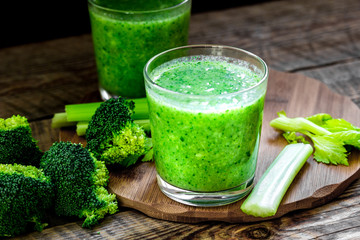 Green vegetable smoothie in glass at wooden background