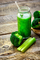 Green vegetable smoothie in glass at wooden background