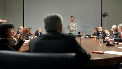 Large audience admires a report and begin clapping. Two young speakers make successful presentation of their new start-up product.